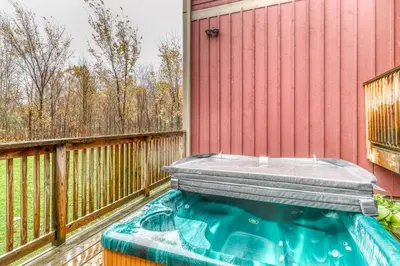 a hot tub on a deck next to a red house at Lucille 109 in Blue Mountains