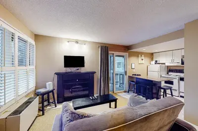 a living room with a couch and a table and a kitchen at Condo 503 at North Creek Resort in Blue Mountains