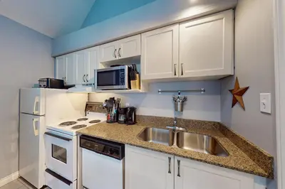 a kitchen with white cabinets and a sink and a microwave at Condo 310 at North Creek Resort in Blue Mountains