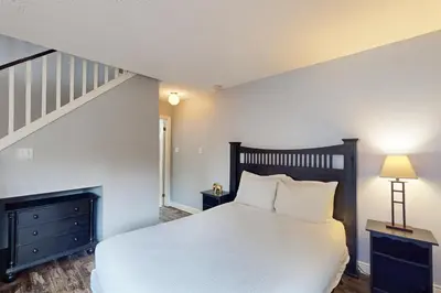 a bedroom with a white bed and a staircase at Condo 310 at North Creek Resort in Blue Mountains