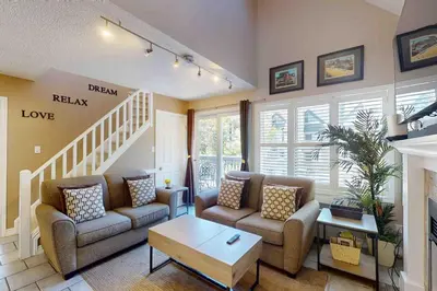 a living room with two couches and a staircase at Condo 713 at North Creek Resort in Blue Mountains