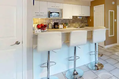 a kitchen with white cabinets and a counter with stools at Condo 713 at North Creek Resort in Blue Mountains