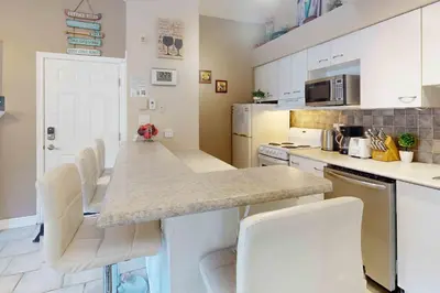a kitchen with white cabinets and a counter with white chairs at Condo 713 at North Creek Resort in Blue Mountains