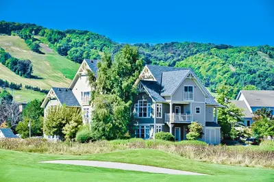 a house on a golf course with mountains in the background at Rivergrass 226 in Blue Mountains