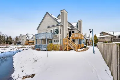 a large house in the snow next to a river at Condo 614 at North Creek Resort in Blue Mountains