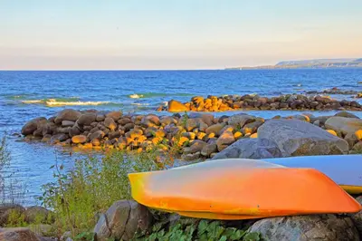 an orange kayak sitting on the rocks near the water at Condo 614 at North Creek Resort in Blue Mountains