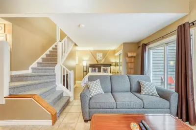a living room with a couch and a staircase at Condo 616 at North Creek Resort in Blue Mountains