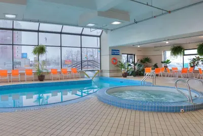 a large swimming pool in a building with orange chairs at Howard Johnson Plaza by Wyndham by the Falls Niagara Falls in Niagara Falls