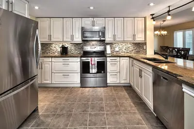a kitchen with white cabinets and a stainless steel refrigerator at Large luxurious upper floor condo in Sierra Lane in Blue Mountains