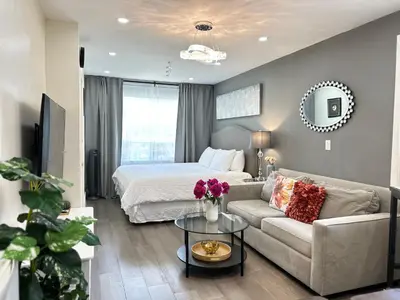 a living room with a bed and a couch at Modern Lux Family Rooms - KingBed - Near Sheppard W Station Toronto in Toronto