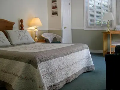 a bedroom with a bed and a desk and a window at Canterbury Inn in Niagara on the Lake
