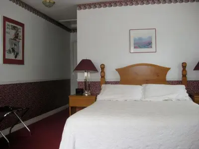 a bedroom with a white bed and a table with a lamp at Canterbury Inn in Niagara on the Lake
