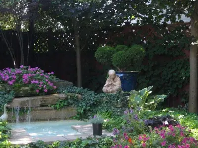 a garden with a statue sitting next to a fountain at Canterbury Inn in Niagara on the Lake