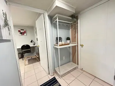 a hallway with a chair and a table in a room at Cozy basement room-Private Bath - Near Subway line 1 - Toronto in Toronto