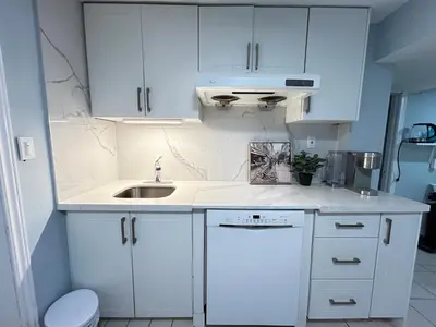 a white kitchen with white cabinets and a sink at Cozy basement room-Private Bath - Near Subway line 1 - Toronto in Toronto