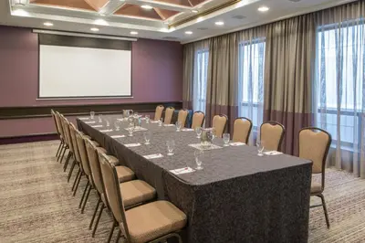 a conference room with a long table and chairs and a screen at Crowne Plaza Kitchener-Waterloo by IHG in Kitchener