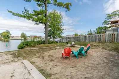 a group of chairs sitting on the sand near the water at Beach1 Riverfront Resort in Wasaga Beach