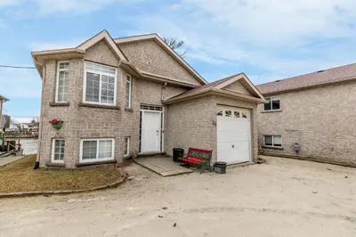 a brick house with two white garage doors at Beach1 Riverfront Resort in Wasaga Beach