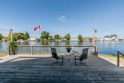 two chairs and a table on a dock near the water at Beach1 Riverfront Resort in Wasaga Beach