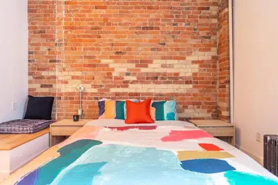 a bed in a room with a brick wall at Gorgeous Park House w Parking on Queen West in Toronto