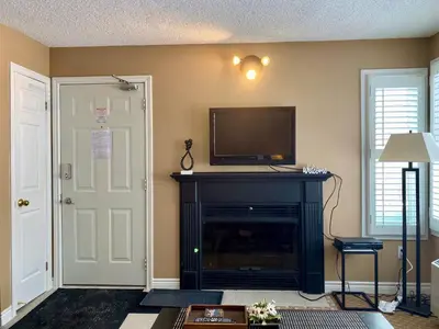 a living room with a fireplace and a flat screen tv at Quiet Hillside Studio - Wifi, Pool, Close to The Village in Blue Mountains