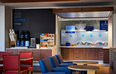 a coffee shop with blue chairs and a table at Holiday Inn Express & Suites - Aurora by IHG in Aurora
