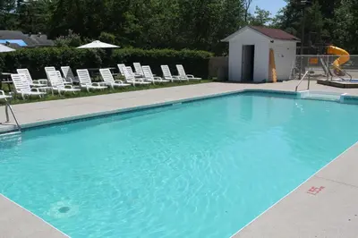 a large blue swimming pool with chairs and chairs at Saga Resort in Wasaga Beach