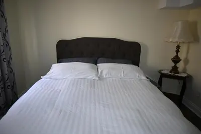 a bed with white pillows and a black headboard at Empire Suite in Niagara Falls