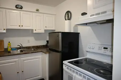 a kitchen with white cabinets and a black refrigerator at Empire Suite in Niagara Falls