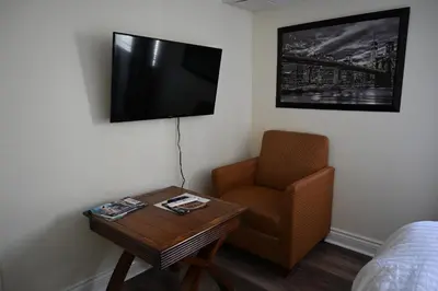 a room with a chair and a tv and a table at Empire Suite in Niagara Falls