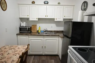 a kitchen with white cabinets and a black refrigerator at Empire Suite in Niagara Falls