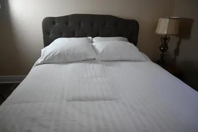 a bed with white sheets and pillows at Elgin Suite in Niagara Falls