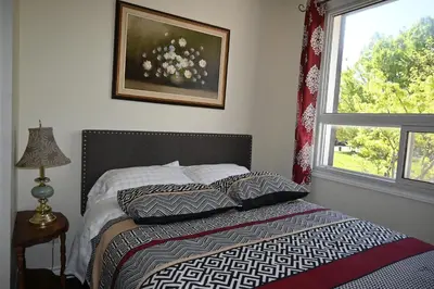 a bedroom with a bed with pillows and a window at Centennial Suite in Niagara Falls