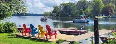 a dock with chairs and boats on a lake at Trent River Cottages in Hastings