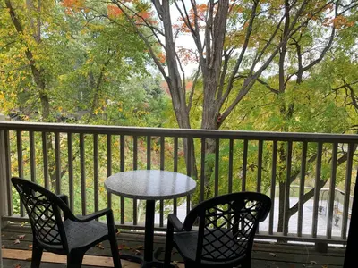 a table and chairs on a porch with a tree at Inn at the Falls in Bracebridge