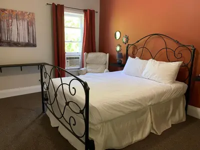 a bedroom with a large bed and a chair at Inn at the Falls in Bracebridge