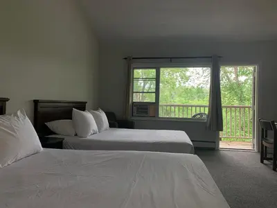 a bedroom with two beds and a large window at Inn at the Falls in Bracebridge