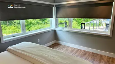 a bedroom with two windows and a bed in it at Orchard Run Chalet in Blue Mountains