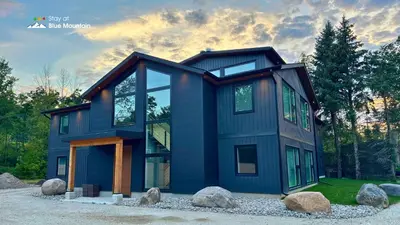 a blue house with windows and rocks at Orchard Run Chalet in Blue Mountains