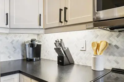 a kitchen with white cabinets and a counter top with utensils at Ski In Out Chateau Ridge Chalet on Ski Run in Blue Mountains