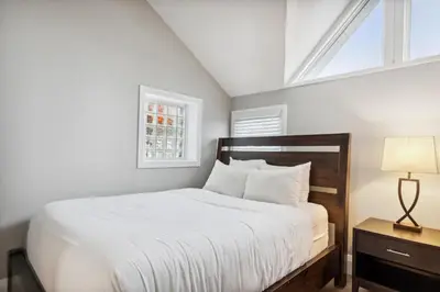 a bedroom with a bed with white sheets and a window at Ski In Out Chateau Ridge Chalet on Ski Run in Blue Mountains
