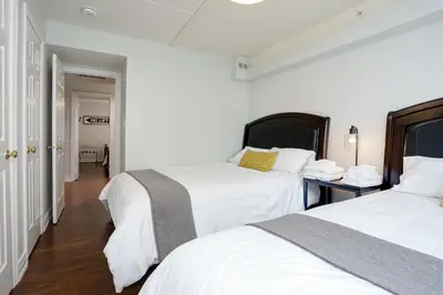 two beds in a room with white walls and wood floors at Blue Mountain, 3 BR - 108 Mountain Walk Chalet in Blue Mountains