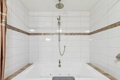 a bath tub in a white tiled bathroom with a shower at 2BR Slopeside in Chateau Ridge Blue Mountains in Blue Mountains