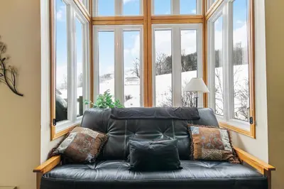 a black leather couch in a room with windows at 2BR Slopeside in Chateau Ridge Blue Mountains in Blue Mountains