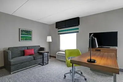 a living room with a couch and a desk with a television at Hampton Inn & Suites Belleville in Belleville