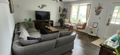 a living room with a couch and a tv at Boho Cottage - Hot tub and close to Beach in Fort Erie