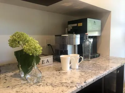 a counter with a vase of flowers and cups on it at Harrogate House Inn in Niagara on the Lake