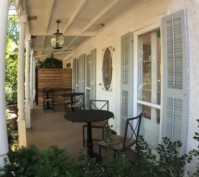 a porch with tables and chairs on a house at Harrogate House Inn in Niagara on the Lake