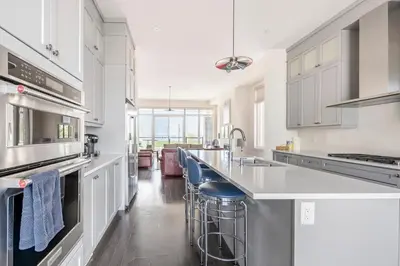 a kitchen with white cabinets and a large island with bar stools at Grand Waterfront Retreat under 1hr from Toronto in Bowmanville