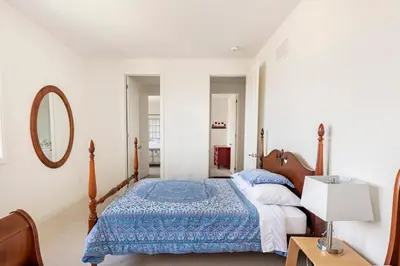 a bedroom with a bed with a blue comforter and a mirror at Grand Waterfront Retreat under 1hr from Toronto in Bowmanville